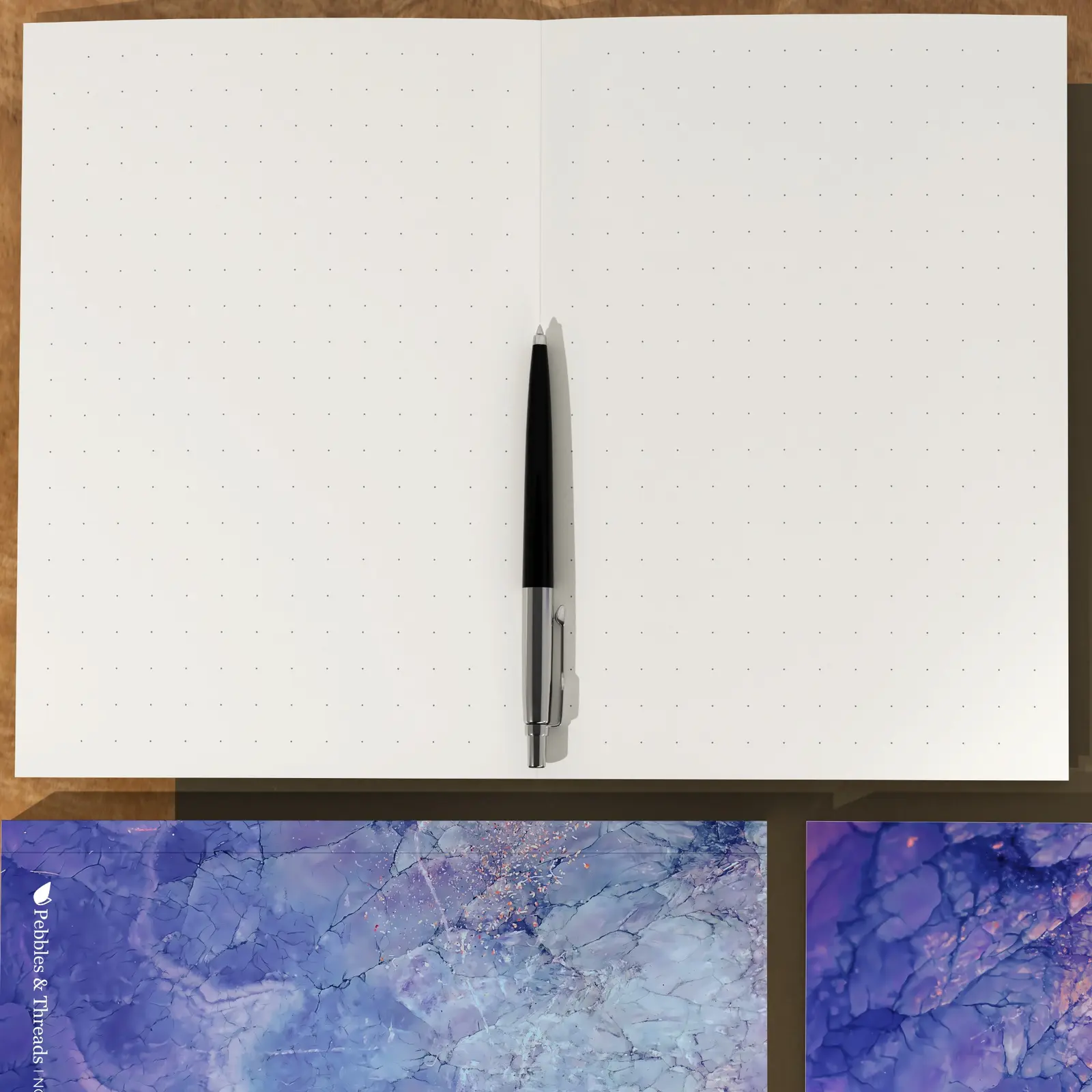 Prime Series notebook open to its subtle dot-grid pages with a pen at the centre